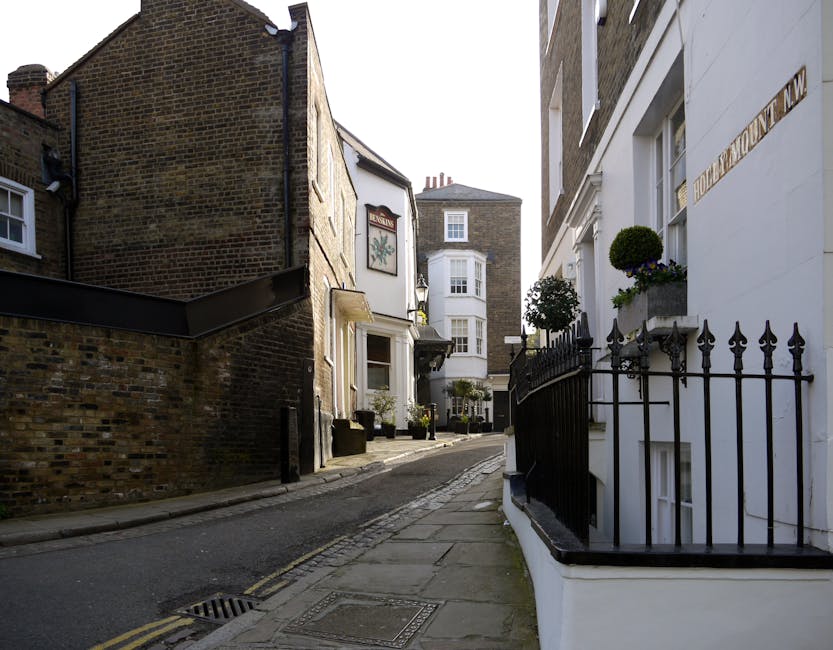 Exterior view of a row of terraced houses on Chestnut Grove in Balham, featuring brick facades with white window frames and small balconies with metal railings. One house has a bright blue door access